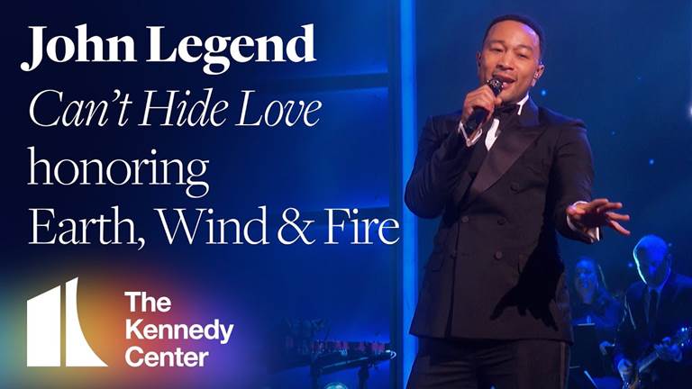 John Legend performing "Can't Hide Love" in a black tuxedo at the 2019 Kennedy Center Honors.