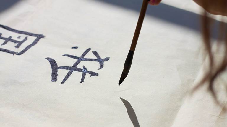 A person painting Chinese calligraphy.