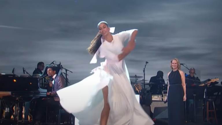 Dancer in white flowing dress performs accompanied by Jon Batiste and Rebecca Luker
