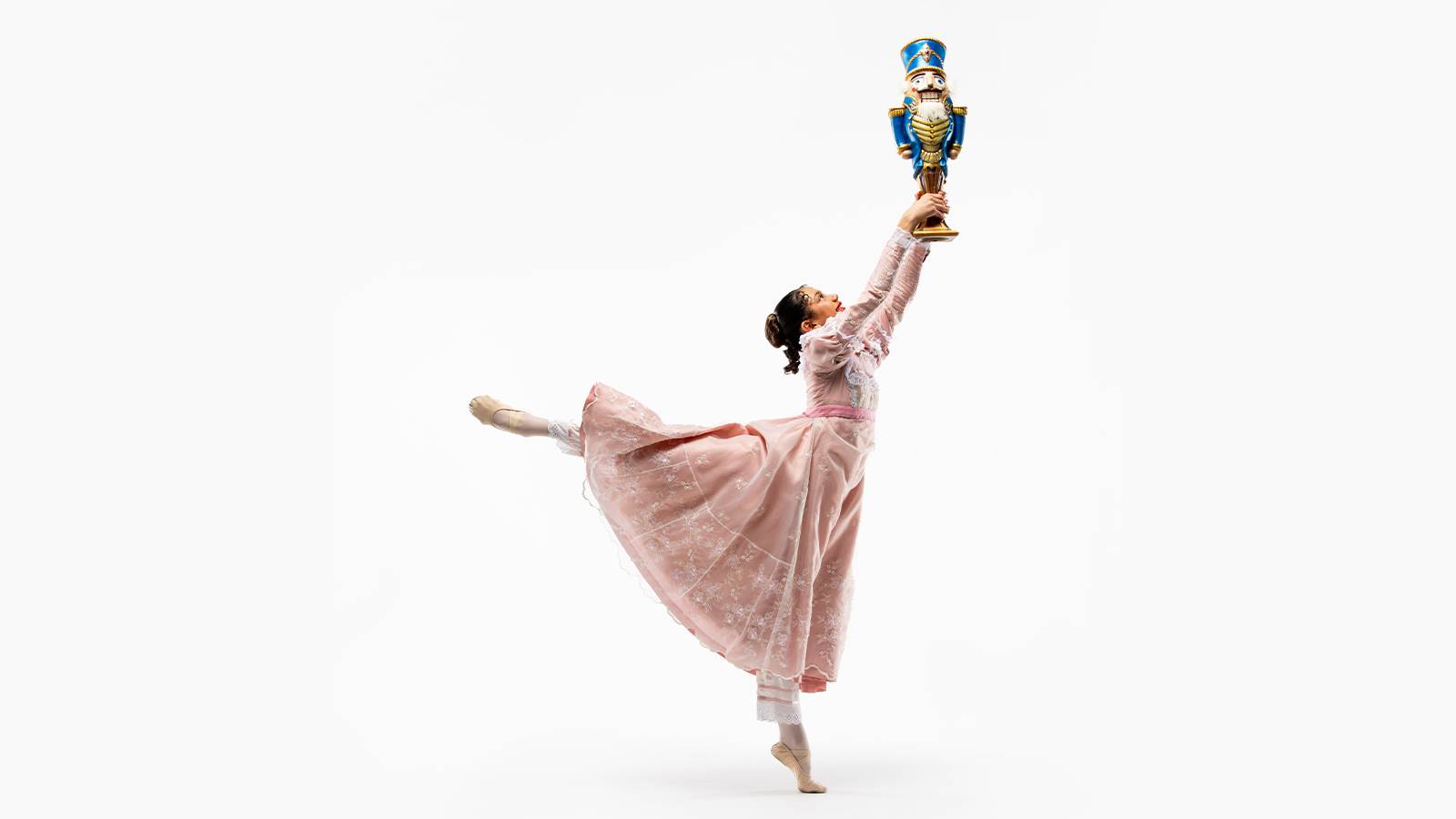 Dancer holds Nutcracker doll up in a ballet pose.